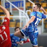 Handballspieler im blauen Trikot wirft den Ball in der Sporthalle Linz.