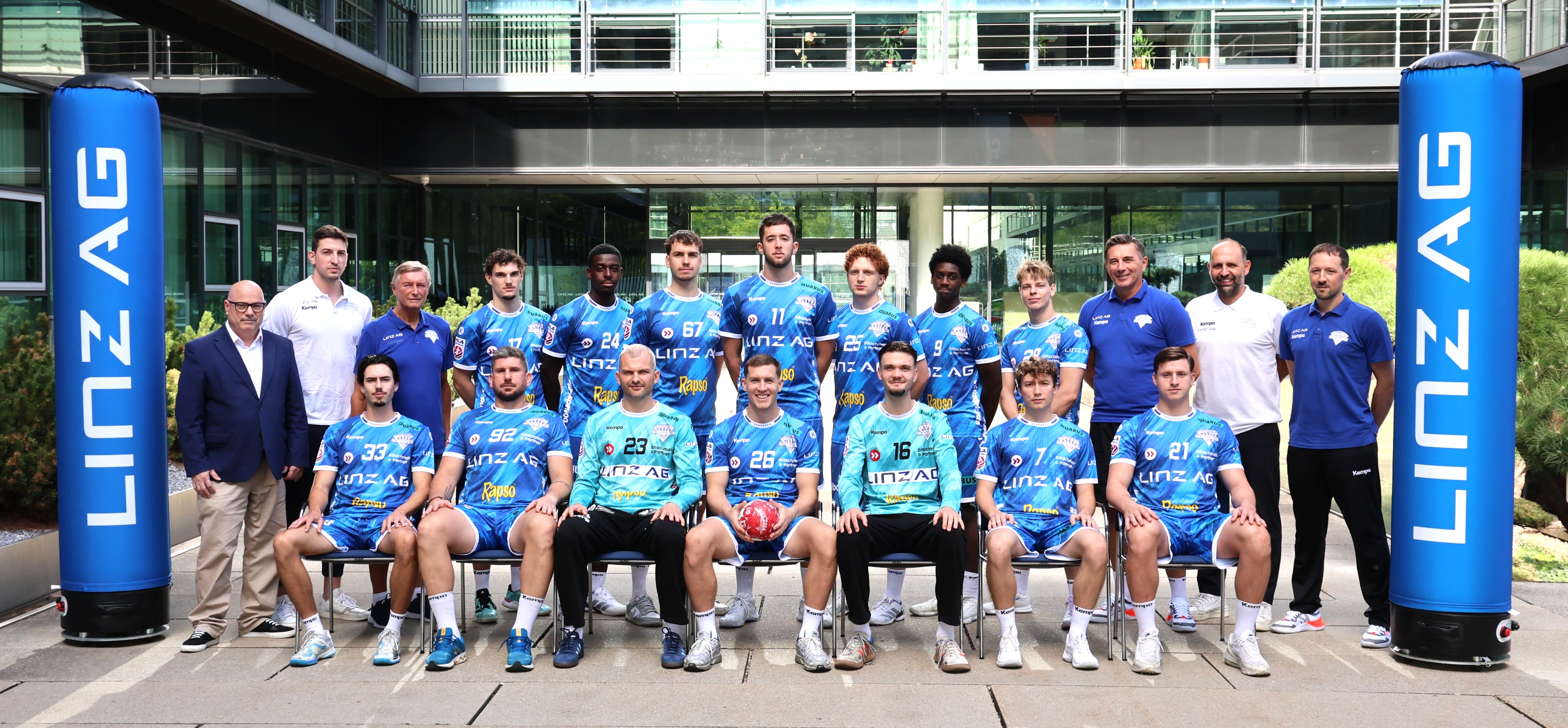 Handballteam Linz AG mit Betreuer und Trainer vor dem Gebäude.