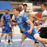 Handballer mit Nummer 25 in blauer Spielkleidung kämpft um den Ball in einer Halle.